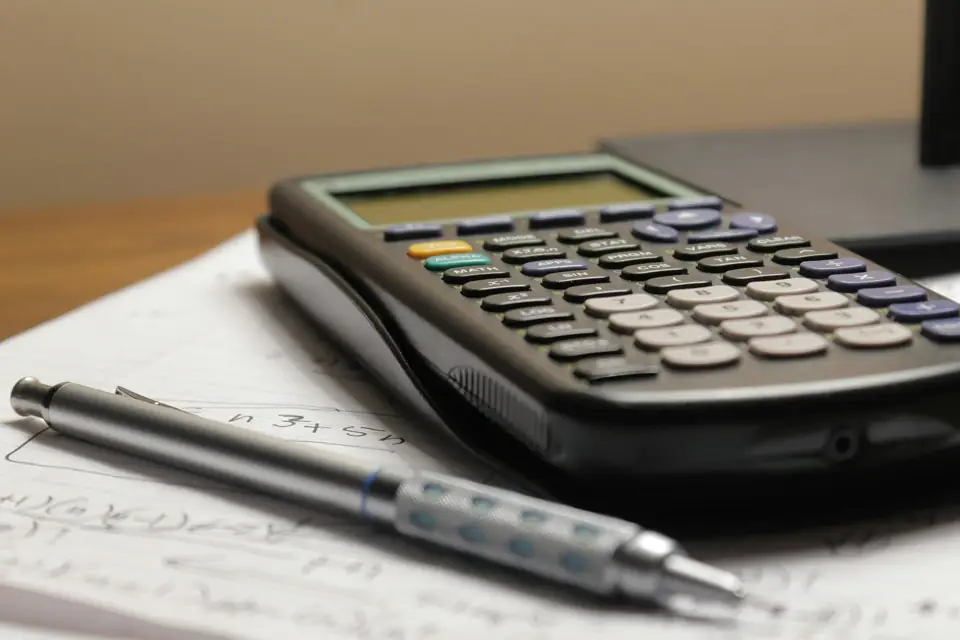 Calculadora e caneta sobre papéis